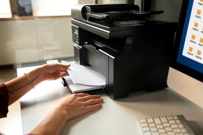 Person removing printed paper from office printer machine