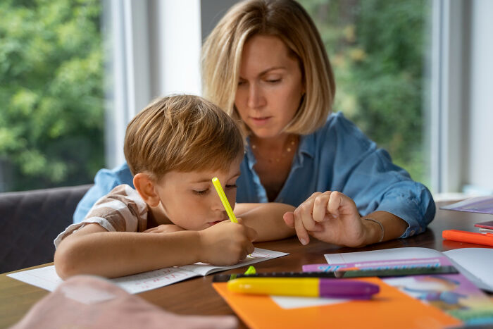Mother helping young boy with homework at home