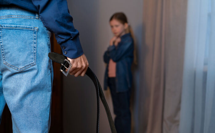 Person holding belt with child standing fearfully in background unsettling thing found about friend
