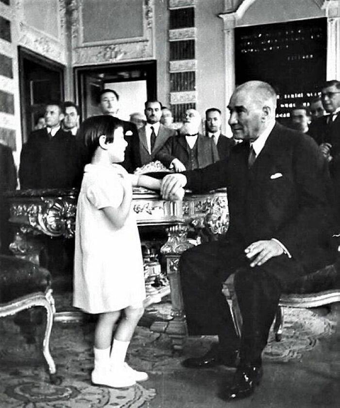 Historic photo of world leader warmly engaging with a child in a formal room