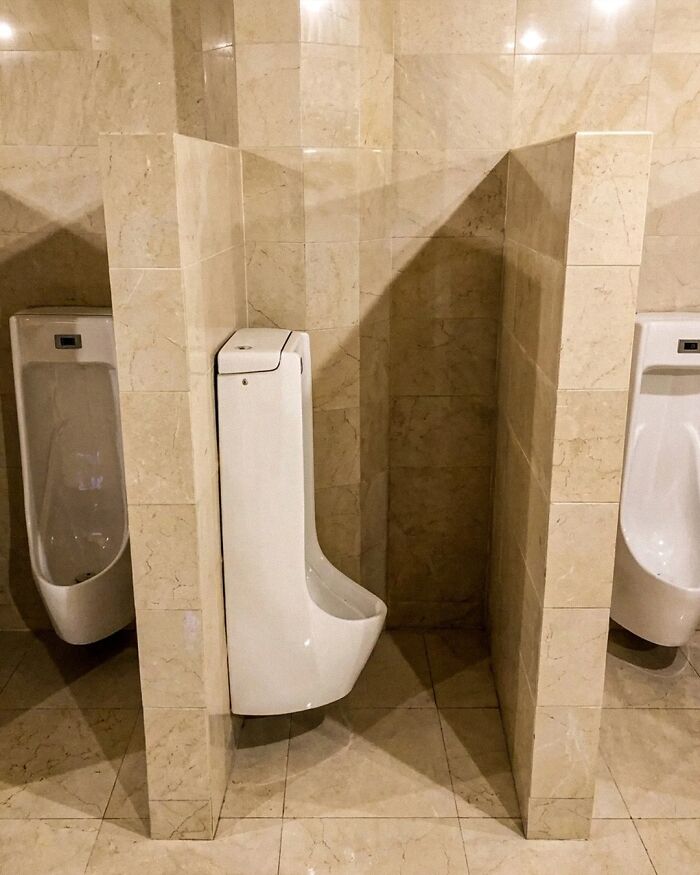 Urinal awkwardly installed with block wall limiting use