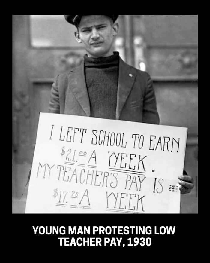 A young man protests low teacher pay with a sign in this historical photo from 1930.