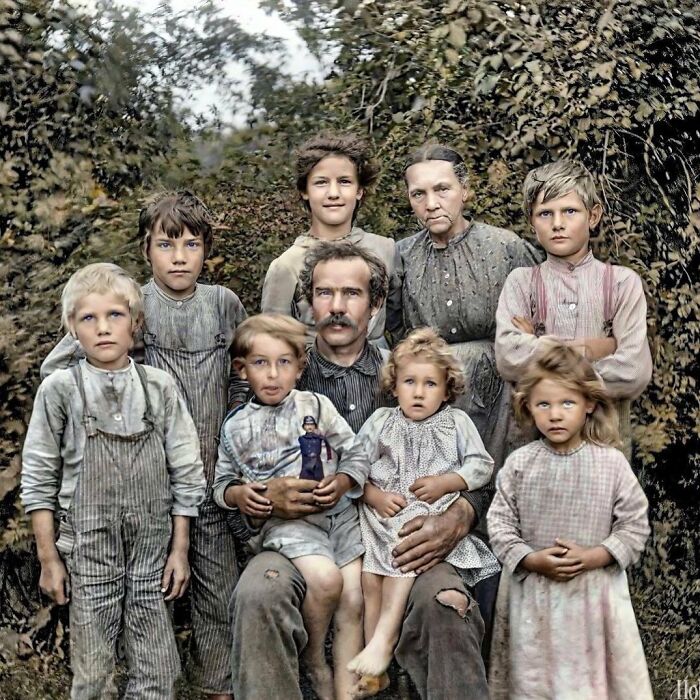 Colorized historical photo of a family, a man and woman with six children, posing outdoors.