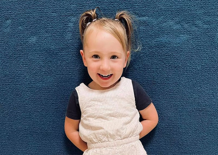 Smiling 4-year-old girl posing indoors on blue carpet Smiling 4-year-old girl posing indoors on blue carpet