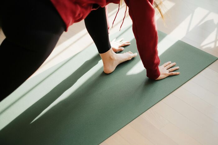 A person in a red hoodie and black leggings on a green yoga mat. This image does not relate to plane interactions.