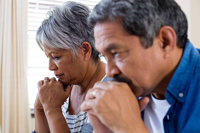 A middle-aged couple, looking concerned and serious, depicting the emotional aspect of a woman told to leave home.