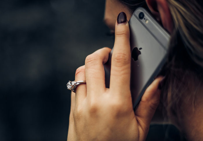 A person with a diamond ring on their finger is holding a smartphone to their ear, making a call about the trespassing incident. A person with a diamond ring on their finger is holding a smartphone to their ear, making a call about the trespassing incident.