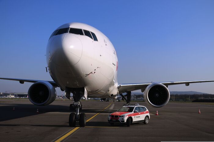 A large commercial plane parked on the tarmac with a police car in front, indicating a plane interaction.