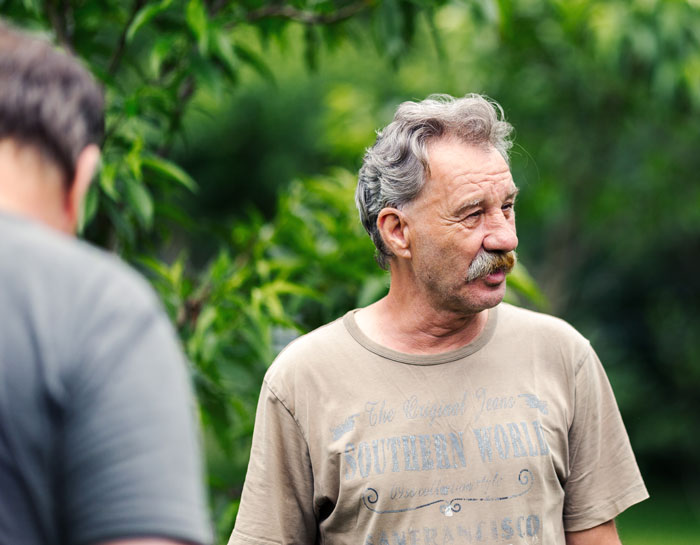 A thoughtful grandpa, with a mustache and gray hair, outside, delivering a reality check to an entitled mom. A thoughtful grandpa, with a mustache and gray hair, outside, delivering a reality check to an entitled mom.