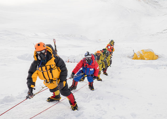 Mountaineers in full gear ascending a snowy slope on Mount Everest, a site connected to the frozen body known as Green Boots.