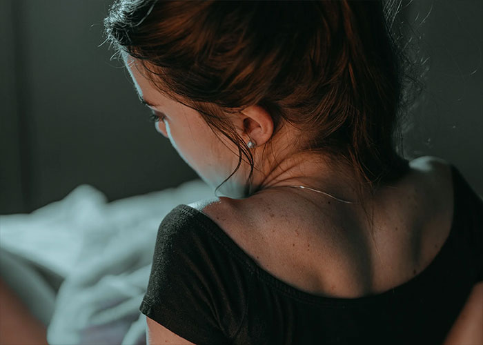 Rear view of a woman with red hair in black top, looking reflective or sad
