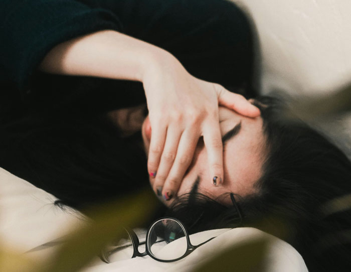 A pregnant woman experiencing contractions, lying down with her hand over her face.