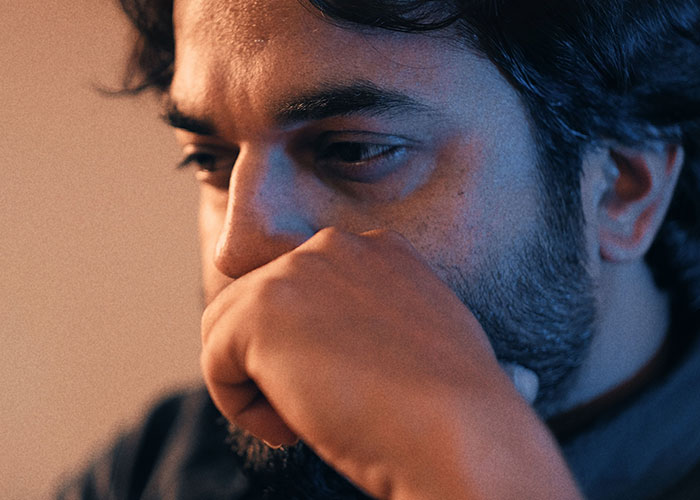 Close-up of man deep in thought with hand partially covering mouth Close-up of man deep in thought with hand partially covering mouth