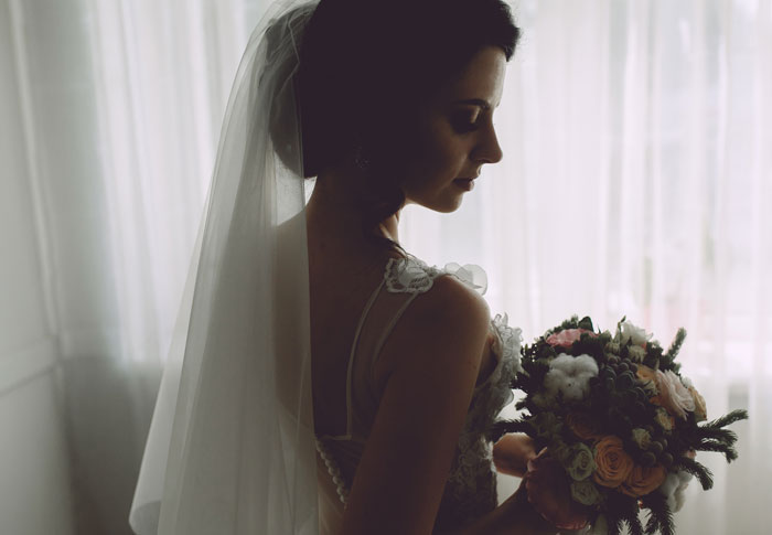 Bride holding bouquet in dim light, wedding mood