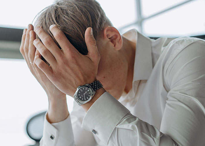 Image of a man with his head in his hands, likely embarrassed by the Woman's Drunken Tantrum at the hotel.