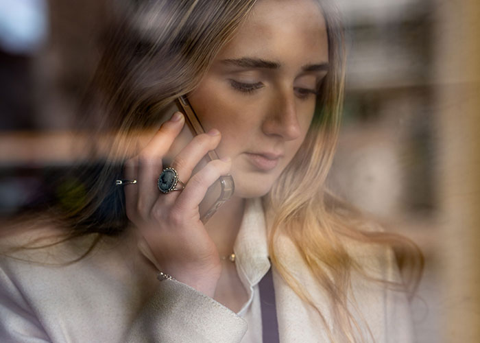 A woman on the phone, her face serious, reflecting the gravity of her suspicions about her husband. A woman on the phone, her face serious, reflecting the gravity of her suspicions about her husband.