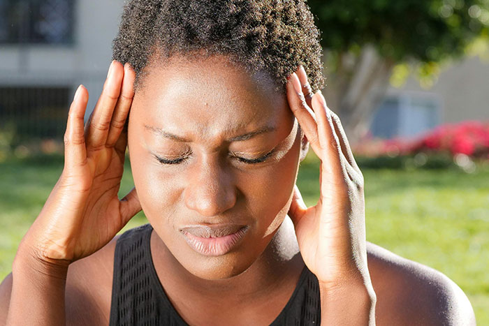 Woman holding her head in pain showing symptoms of a headache