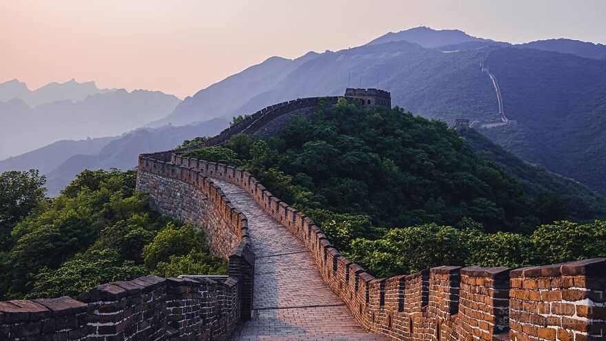 Great Wall of China winding through forested hills during sunset