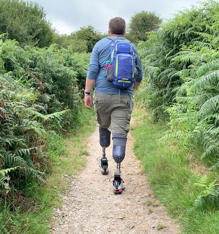 Man with double leg prosthetics hiking on forest trail Man with double leg prosthetics hiking on forest trail