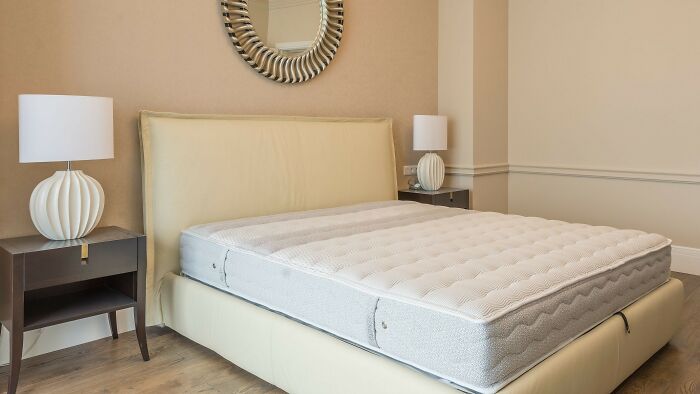 Minimalist bedroom with mattress on cream bed frame and bedside lamps