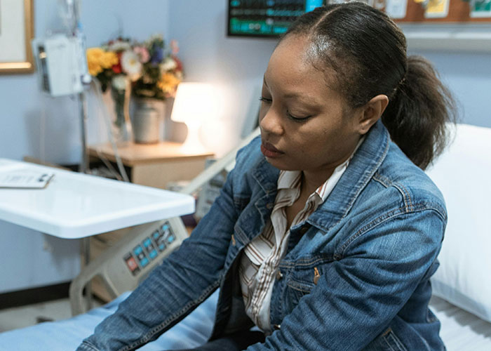Worried woman sitting in hospital bed depicting legal offense context
