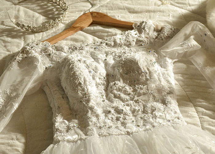 Detailed lace wedding dress on hanger, bridal gown close-up