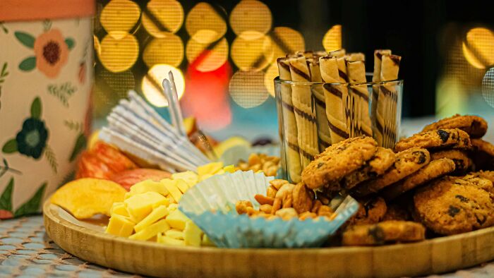 Assorted snacks and cookies on a wooden platter with colorful lights