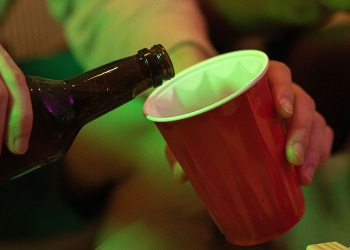 Pouring drink from bottle into cup at party indicating time to leave immediately