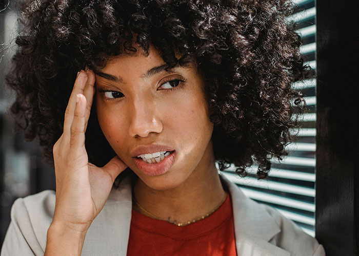 A woman with curly hair holds her head, expressing frustration as kids realize they can't keep contact with parents.