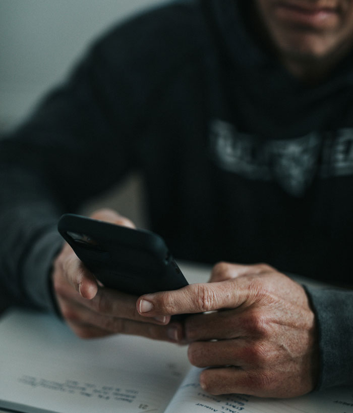 A person holding a smartphone, engrossed in something on the screen, reflecting DNA testing stories.