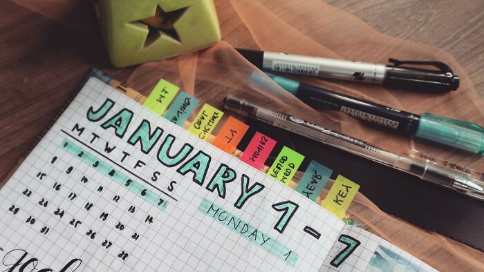 A calendar with colorful sticky notes, pens, and a green star-shaped ornament, representing planning for a date.