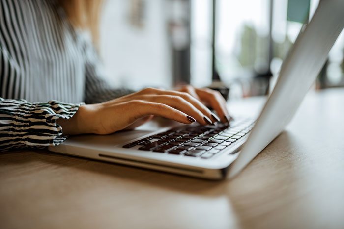 Woman typing on laptop keyboard in casual setting Woman typing on laptop keyboard in casual setting