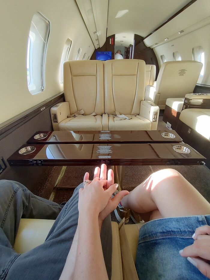 A couple holding hands inside a luxurious private plane cabin, experiencing a special plane interaction.