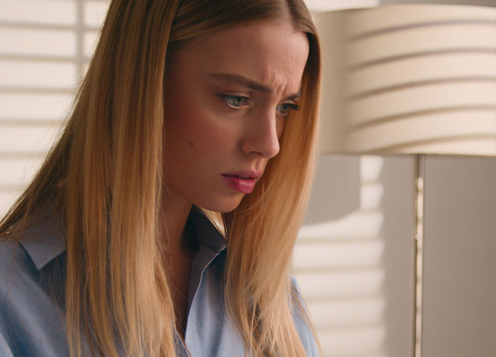Sad young woman looking down and worried indoors Sad young woman looking down and worried indoors