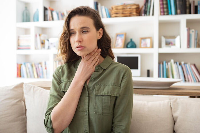 Woman holding throat with discomfort illustrating human body health issues