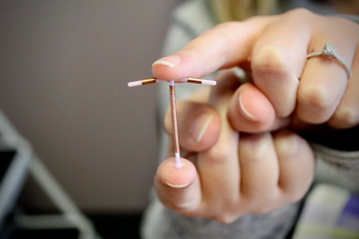 A hand holding an IUD, symbolizing pain and discomfort associated with medical procedures or contraception.