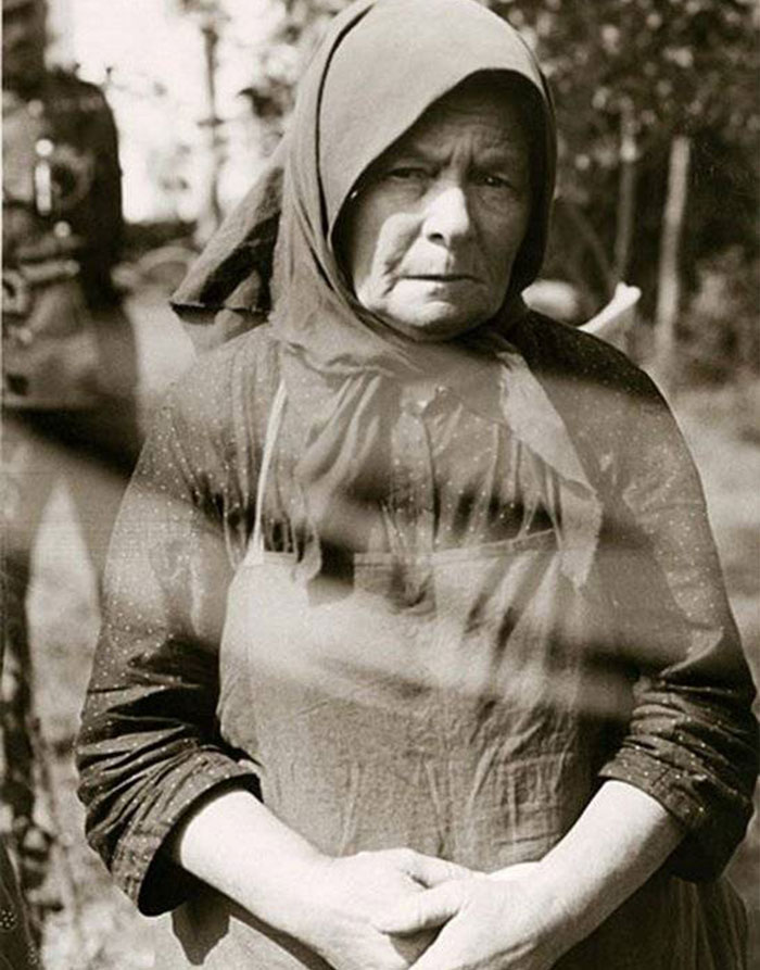 Older woman wearing traditional headscarf looking serious in outdoor historical photo Older woman wearing traditional headscarf looking serious in outdoor historical photo