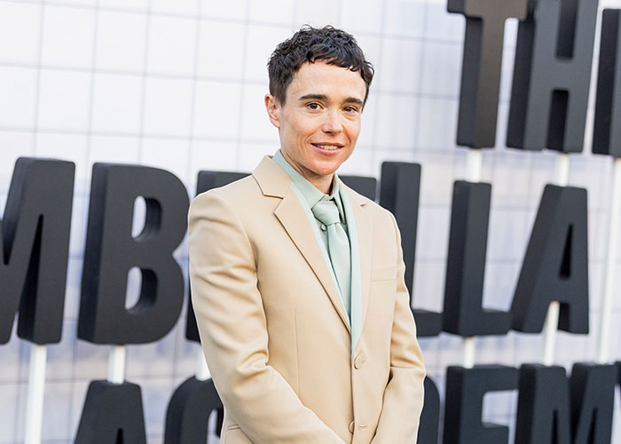 Elliot Page poses on a red carpet, looking confident and healthy after getting hooked on boxing for his shredded physique.