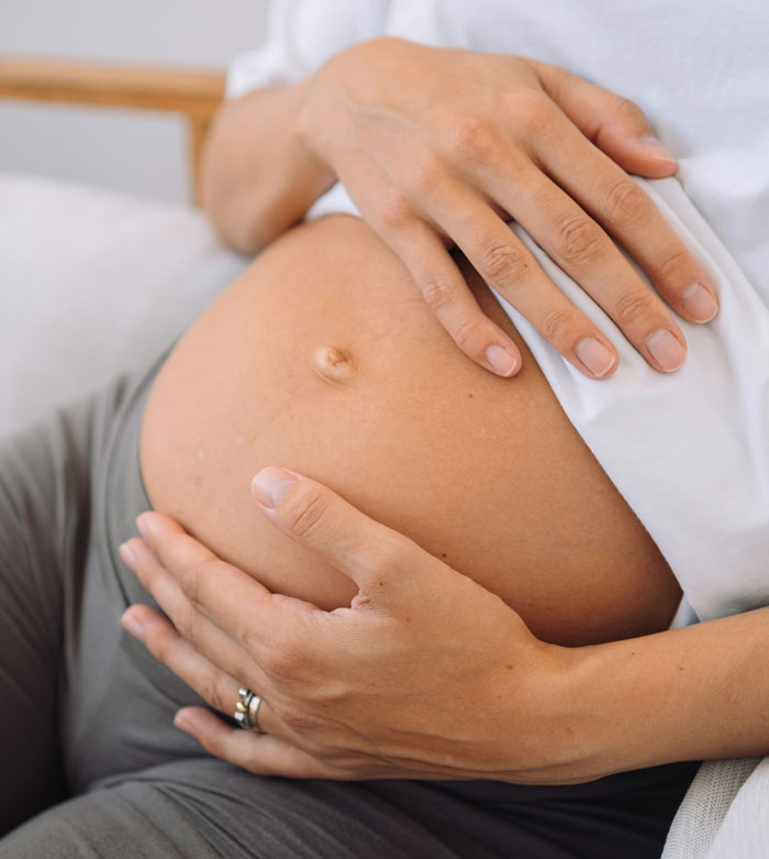 Close-up of a pregnant woman's belly, hands gently resting on her expanding stomach, feeling contractions.