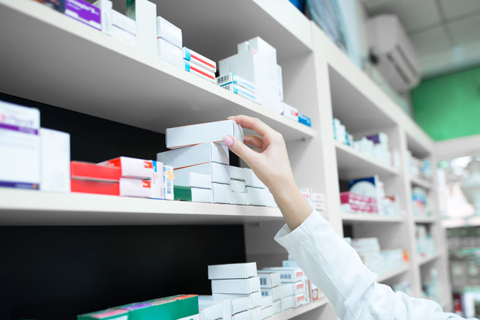 Pharmacist reaching for medicine boxes on shelves in a pharmacy Pharmacist reaching for medicine boxes on shelves in a pharmacy