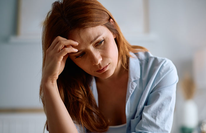 Sad woman with red hair sadness reflecting on MOH experience