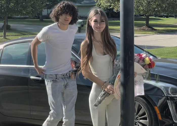 Young couple standing beside a black car holding flowers Young couple standing beside a black car holding flowers