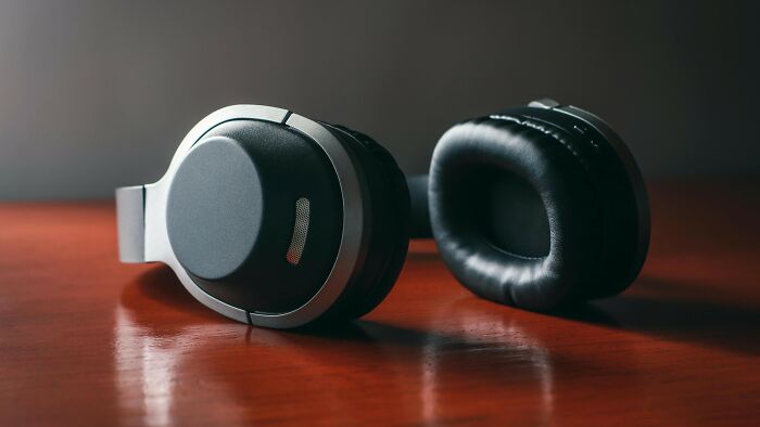 Modern wireless headphones resting on wooden surface