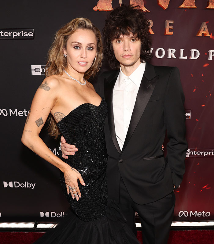 Miley Cyrus and man posing on red carpet at movie premiere Miley Cyrus and man posing on red carpet at movie premiere