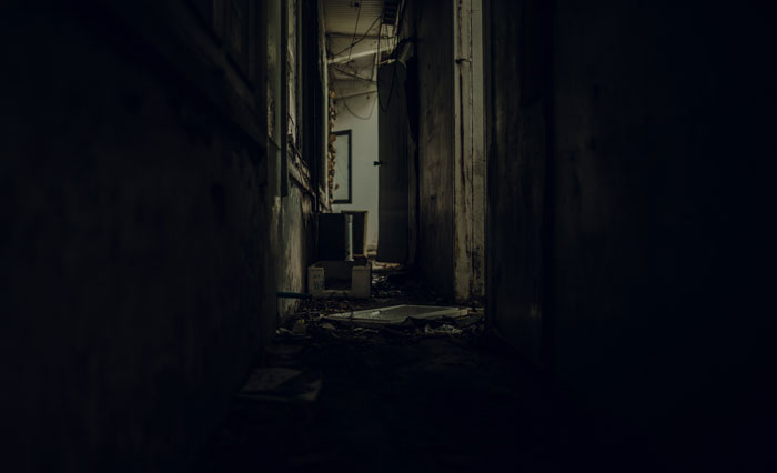 Dark abandoned hallway with debris on floor