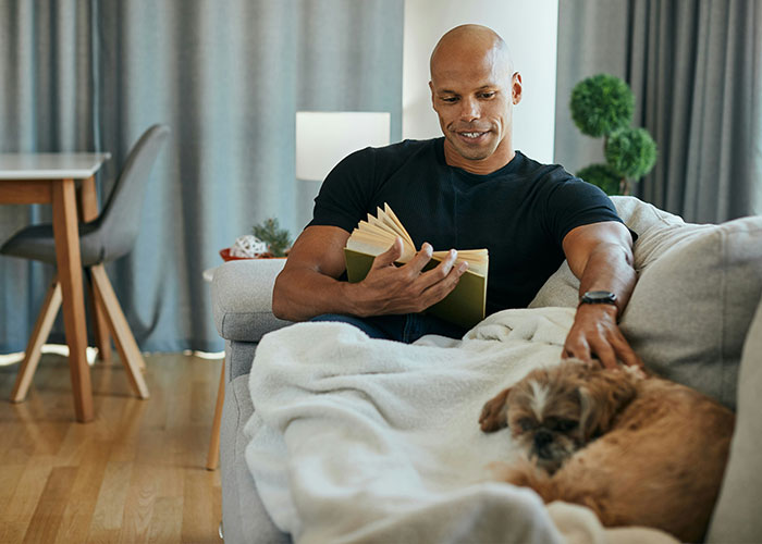 Man reading book while petting calm dog, ideal quiet dog breed