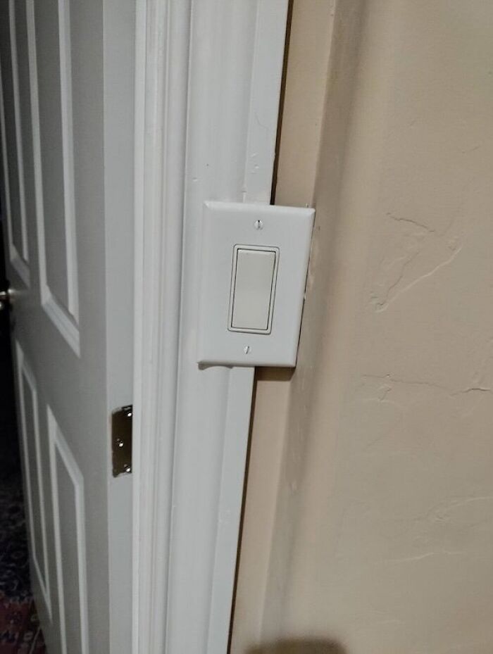 Light switch awkwardly placed on door trim displaying design fail
