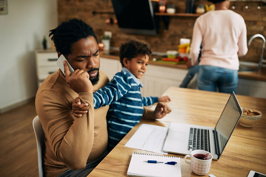 Father distracted on phone while child seeks attention during family conflict resolution