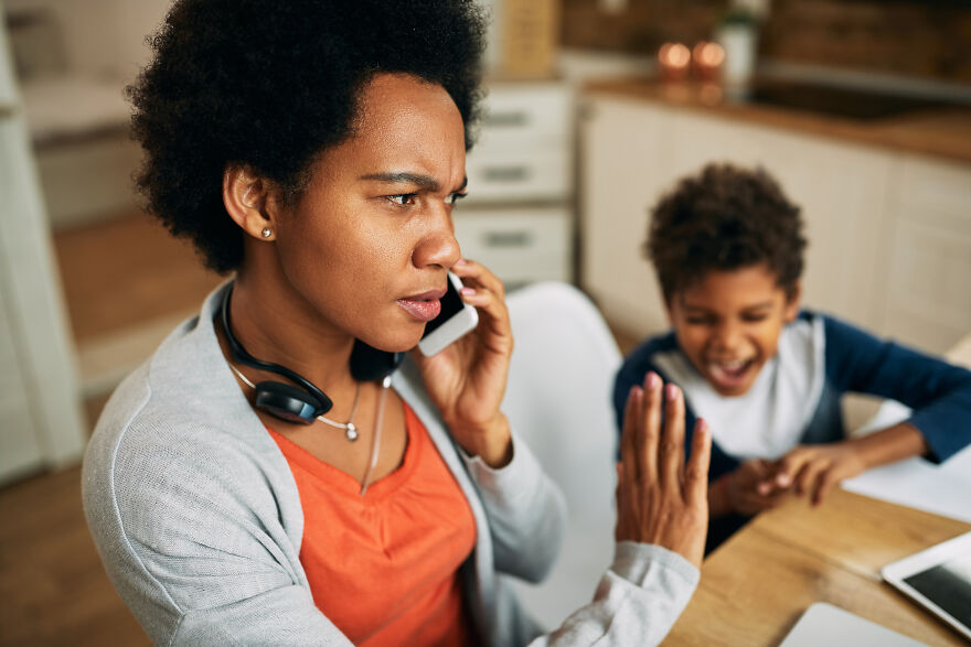 Stressed mother on phone ignoring child demanding attention