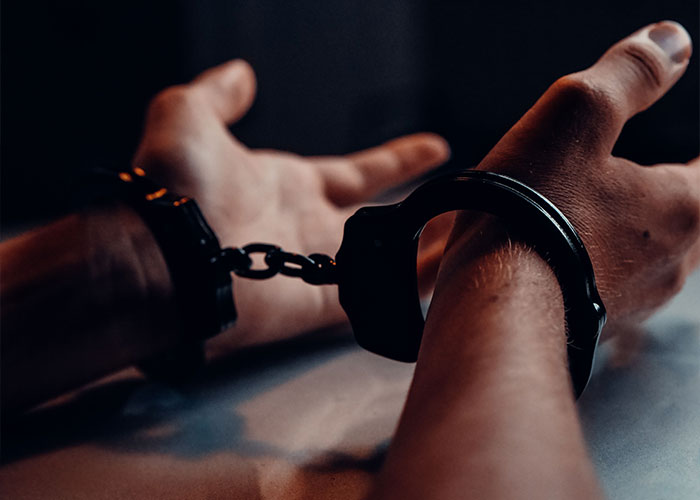 Hands in handcuffs, symbolizing the arrest of a millionaire connected to UK royals for pushing woman in front of bus. Hands in handcuffs, symbolizing the arrest of a millionaire connected to UK royals for pushing woman in front of bus.